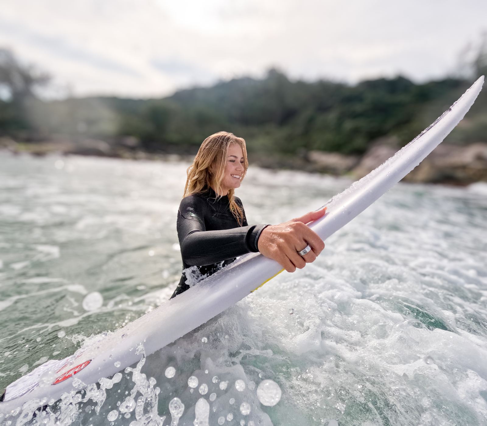 Surfista saindo da água com prancha, usando o Mormaii Ring