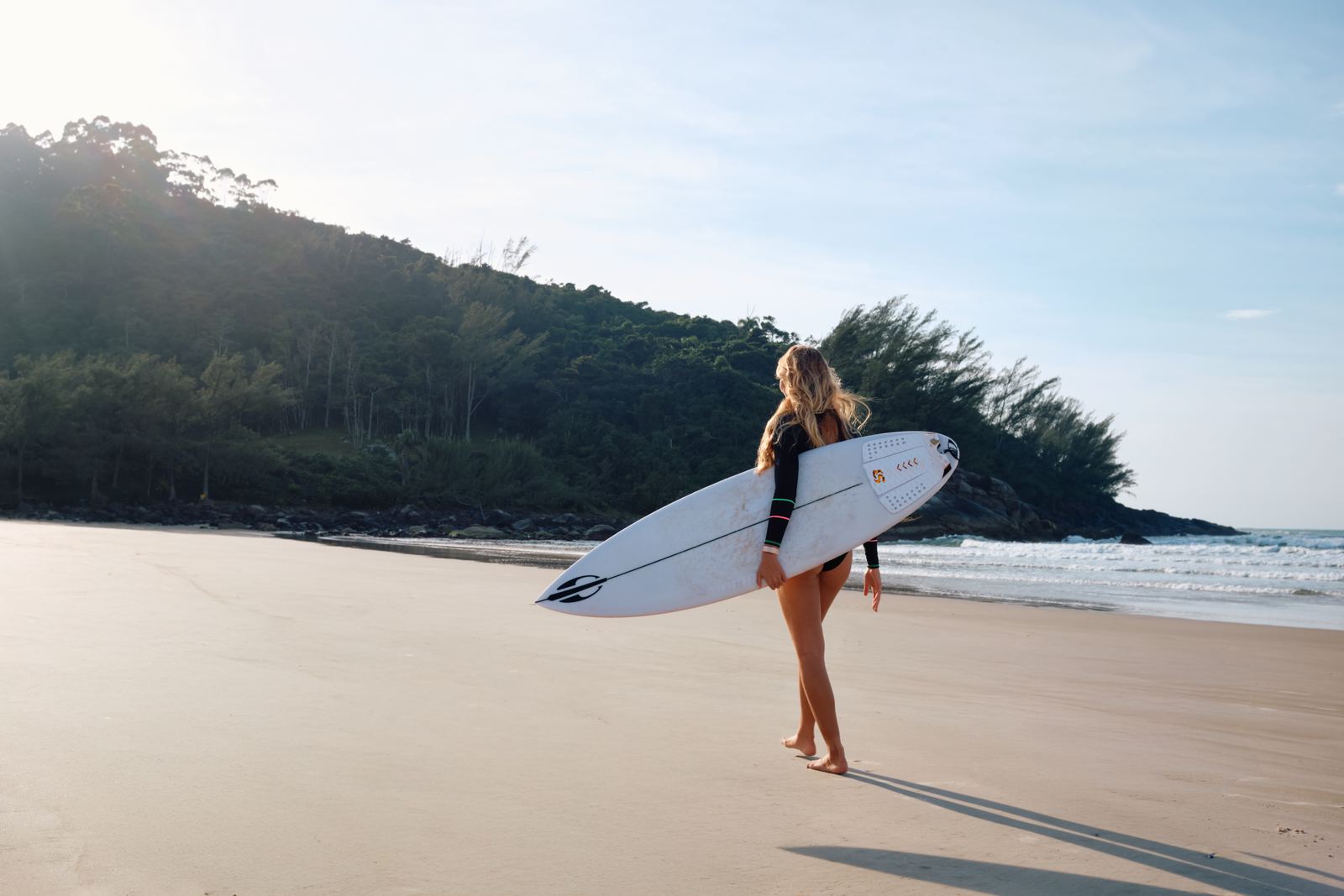 Surfista caminhando na praia ao amanhecer